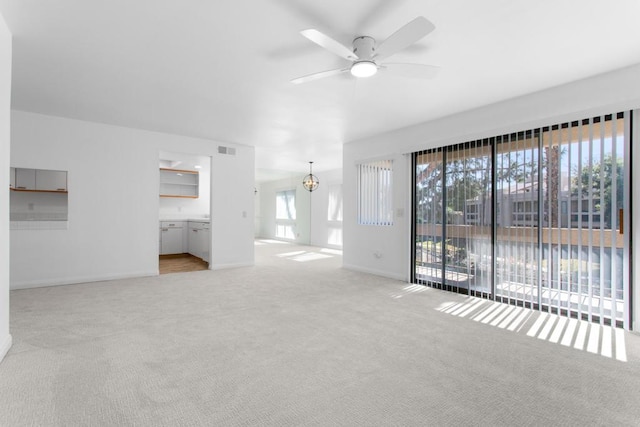 unfurnished living room featuring ceiling fan with notable chandelier and light colored carpet