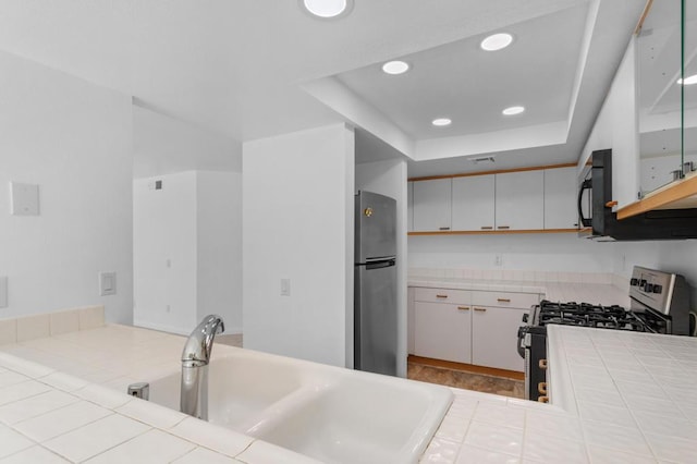 kitchen featuring white cabinetry, stainless steel appliances, a raised ceiling, and sink