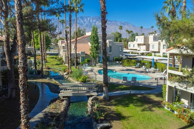 view of swimming pool featuring a patio, a mountain view, and a lawn