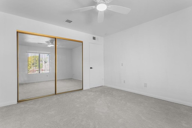 unfurnished bedroom featuring light colored carpet, ceiling fan, and a closet