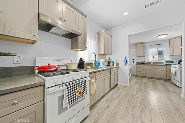 kitchen featuring sink, washer and clothes dryer, gas range gas stove, and light hardwood / wood-style flooring