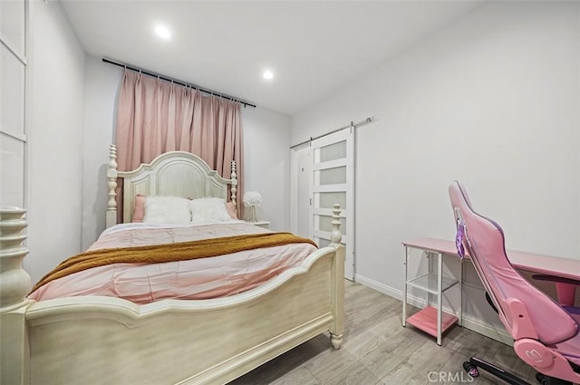 bedroom featuring a barn door and light wood-type flooring