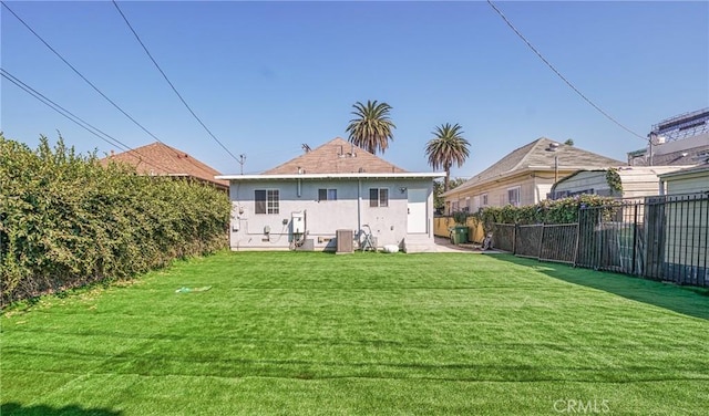 rear view of house featuring cooling unit and a yard