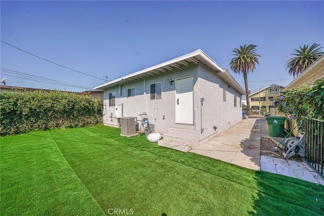 rear view of house with a lawn and central AC unit