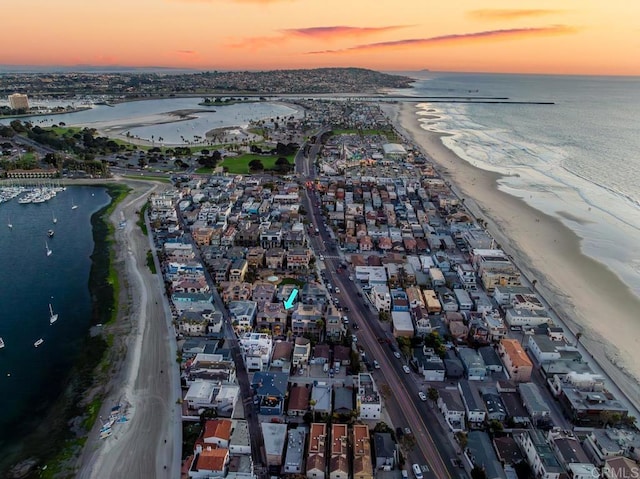 aerial view at dusk with a water view and a view of the beach