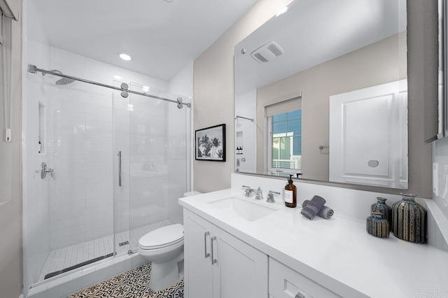 bathroom with a shower with door, toilet, vanity, and tile patterned flooring