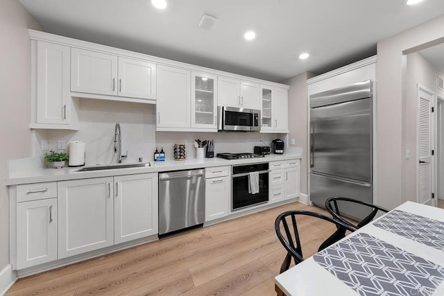 kitchen featuring stainless steel appliances, light hardwood / wood-style floors, white cabinetry, and sink