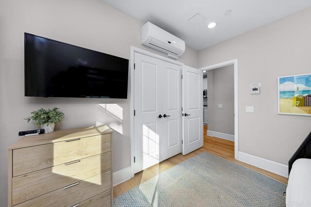 bedroom featuring light hardwood / wood-style floors and a wall mounted AC