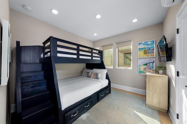 bedroom featuring a wall mounted AC and light wood-type flooring