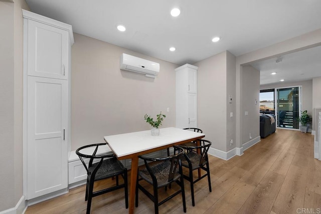 dining room featuring a wall mounted AC and light hardwood / wood-style floors