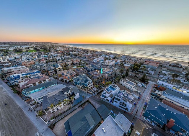 aerial view at dusk with a water view and a view of the beach