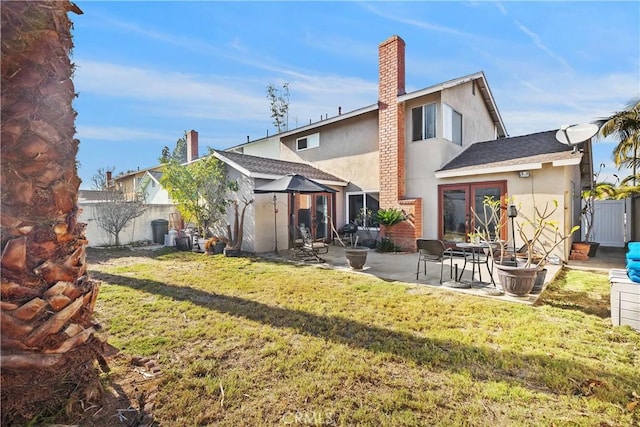 back of property with french doors, a patio, and a lawn