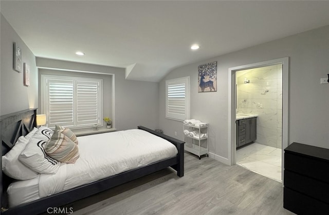 bedroom featuring connected bathroom and light hardwood / wood-style flooring