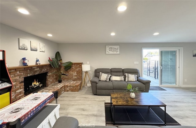 living room featuring a brick fireplace and light wood-type flooring