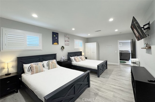 bedroom featuring a closet, multiple windows, and light hardwood / wood-style flooring