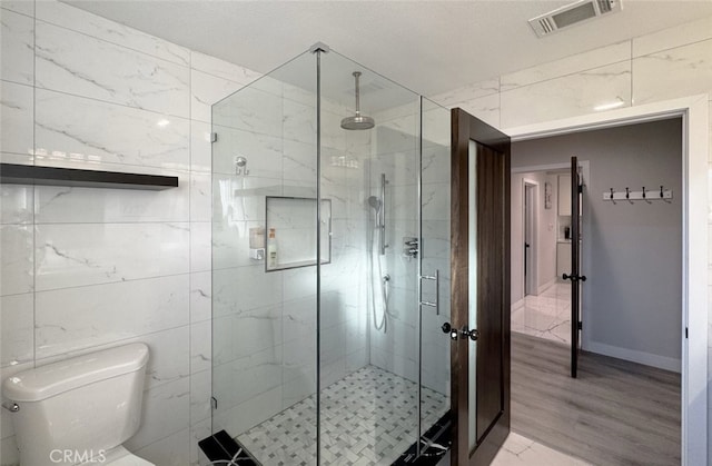 bathroom featuring toilet, hardwood / wood-style floors, and a shower with door