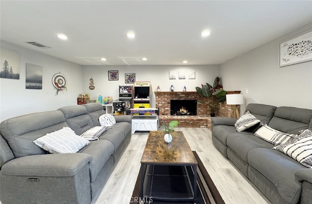 living room with a brick fireplace and light hardwood / wood-style flooring