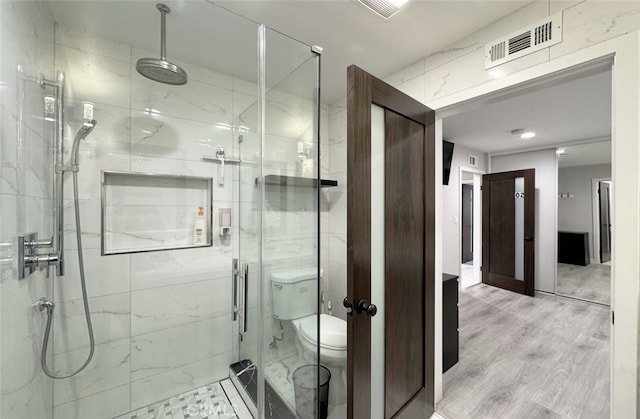 bathroom with toilet, wood-type flooring, and an enclosed shower