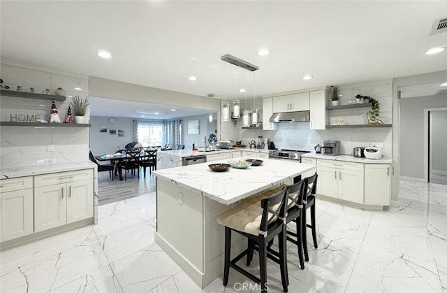 kitchen featuring backsplash, a kitchen breakfast bar, hanging light fixtures, a kitchen island, and stainless steel dishwasher