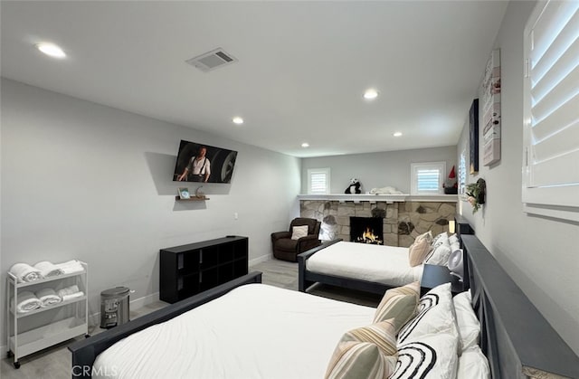 bedroom with a stone fireplace and light wood-type flooring