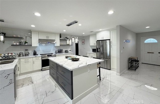 kitchen featuring white cabinets, pendant lighting, stainless steel appliances, and a kitchen island