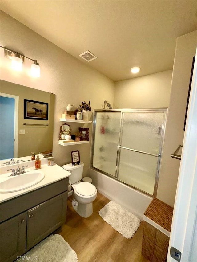 full bathroom with toilet, bath / shower combo with glass door, wood-type flooring, and vanity