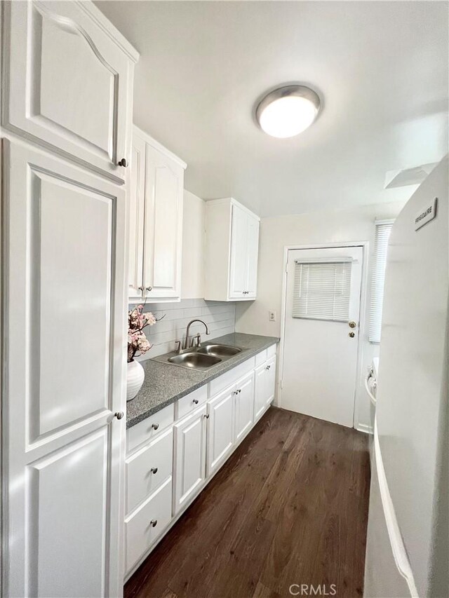 kitchen featuring white cabinetry, sink, dark hardwood / wood-style flooring, backsplash, and white refrigerator