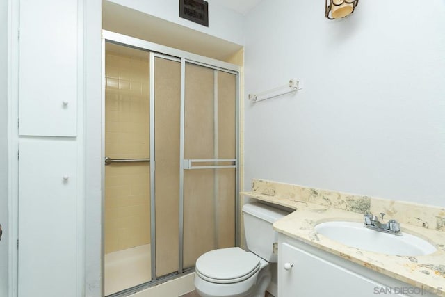 bathroom featuring toilet, vanity, and a shower with door