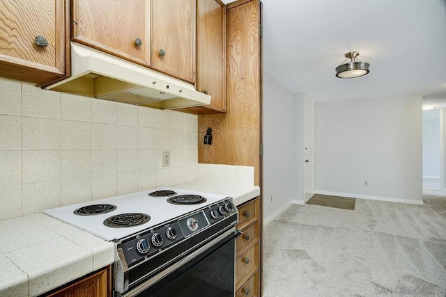 kitchen with tile countertops, range with electric stovetop, decorative backsplash, and light colored carpet