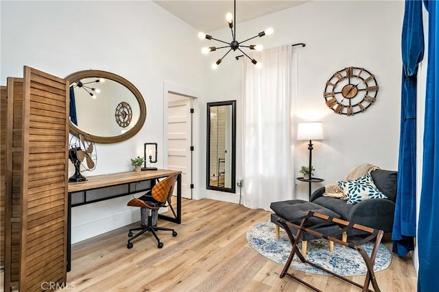 office area featuring a towering ceiling, light wood finished floors, and a notable chandelier