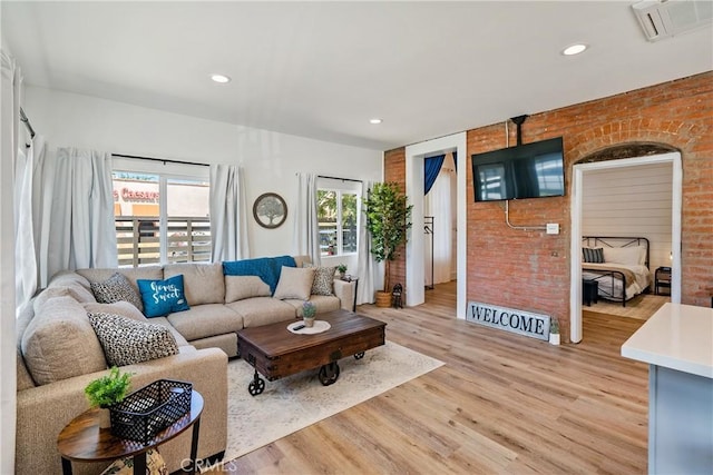 living room featuring light hardwood / wood-style flooring and brick wall