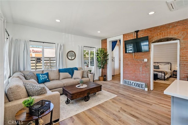 living area featuring brick wall, light wood-style flooring, visible vents, and recessed lighting