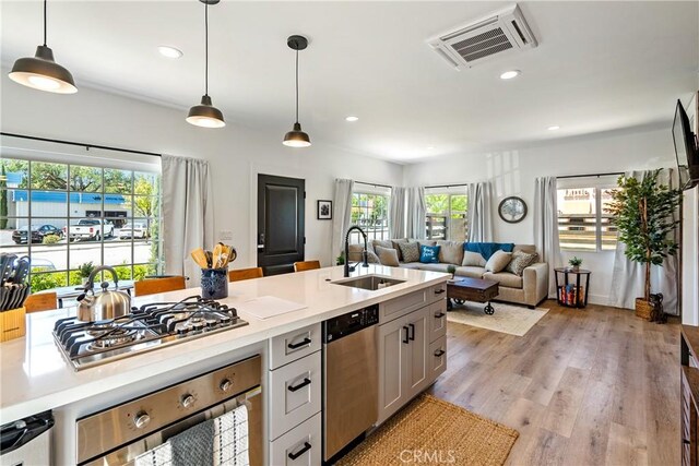 kitchen with pendant lighting, appliances with stainless steel finishes, plenty of natural light, and sink