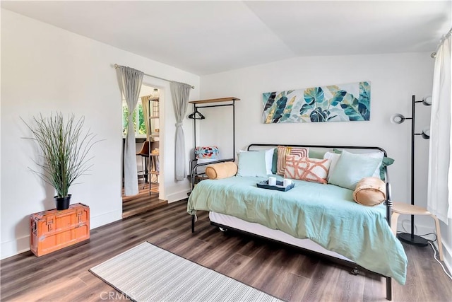 bedroom featuring baseboards, vaulted ceiling, and wood finished floors