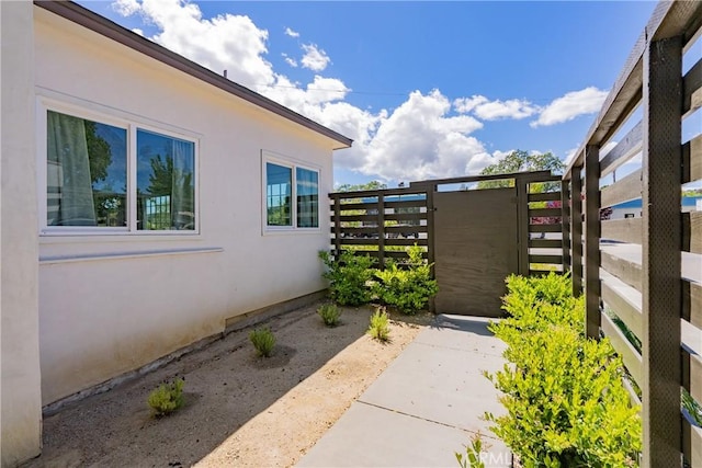 view of home's exterior with fence, a gate, and stucco siding