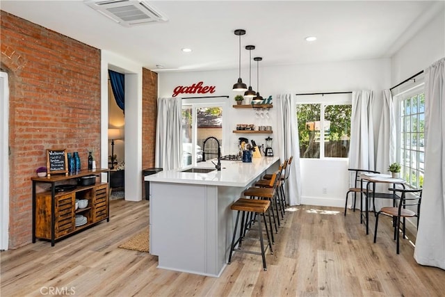 kitchen with light wood-style flooring, visible vents, a kitchen breakfast bar, and a sink