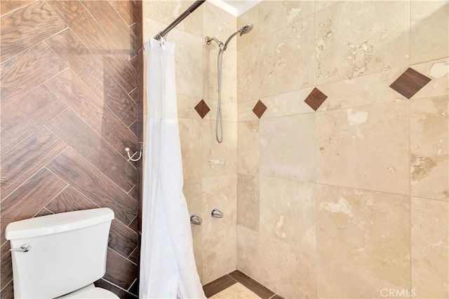 bathroom featuring tiled shower and toilet