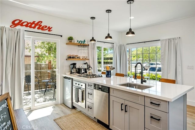 kitchen with stainless steel appliances, light wood-type flooring, light countertops, and a sink