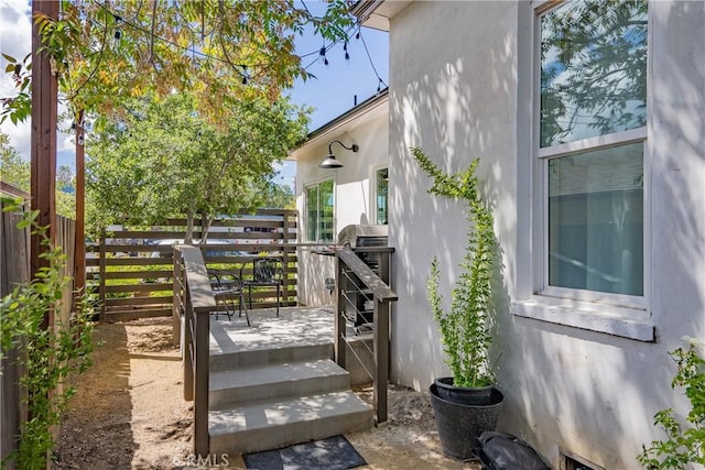 view of side of home featuring stucco siding, fence, and a wooden deck