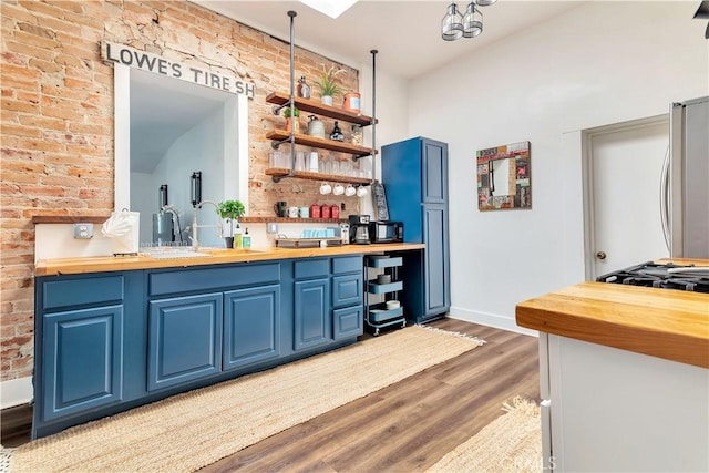 bar with a sink, brick wall, wood finished floors, and freestanding refrigerator