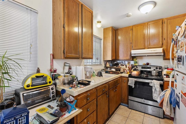 kitchen with tile counters, light tile patterned floors, sink, and stainless steel electric stove