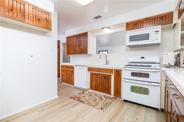 kitchen with sink, white appliances, and light hardwood / wood-style flooring