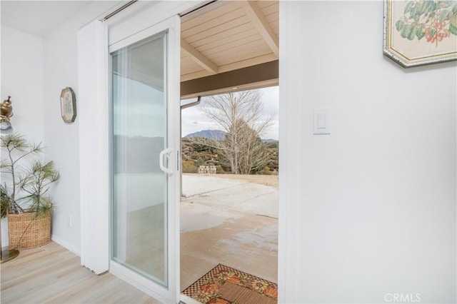 doorway featuring light hardwood / wood-style flooring and beamed ceiling