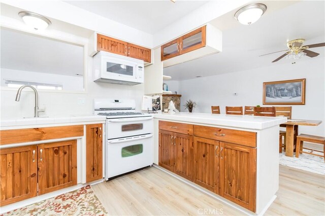 kitchen with white appliances, light hardwood / wood-style floors, sink, kitchen peninsula, and ceiling fan