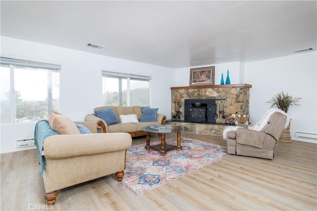 living room featuring a wood stove, light hardwood / wood-style flooring, and a baseboard radiator