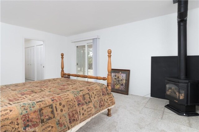 carpeted bedroom with a closet and a wood stove