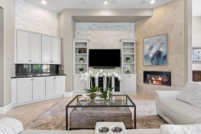 living room with built in shelves, a fireplace, sink, and light tile patterned floors