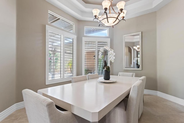 dining space with a notable chandelier, a raised ceiling, and a wealth of natural light