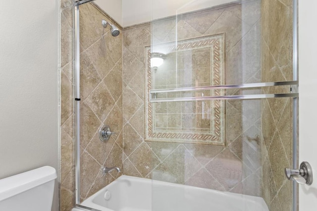 bathroom featuring toilet and shower / bath combination with glass door