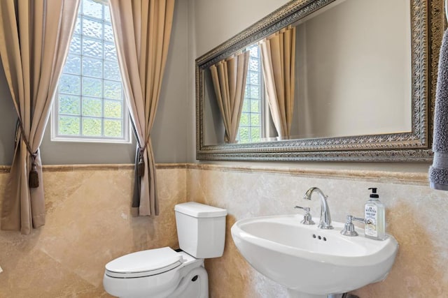 bathroom with toilet, sink, and tile walls